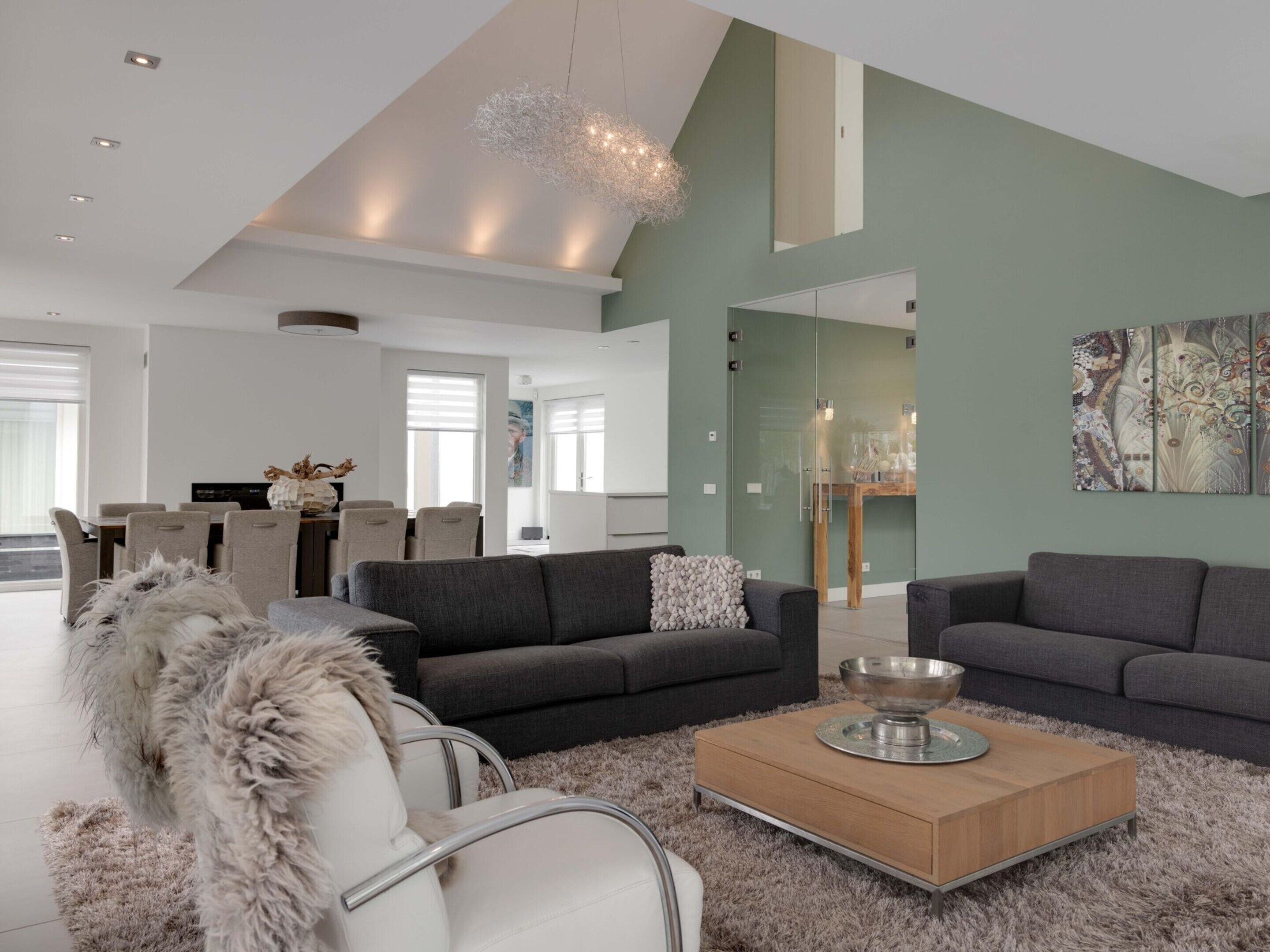 A modern living room with grey sofas, a white armchair, and a wooden coffee table.