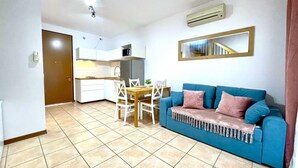 Um espaço compacto para viver, com cozinha compacta, área de jantar e sofá azul.