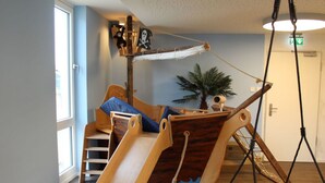 A nautical-themed playroom with a slide, a hanging rope swing, and a ship-shaped bed. - Seaside, South Cape Apartment D5 (Neustadt in Holstein)
