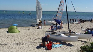 A beach with sailboats, a tent, and people by the water. - Seaside, South Cape Apartment D5 (Neustadt in Holstein)