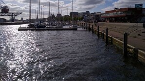 A marina with boats docked, a pier, and buildings in the background. - Holiday Apartment Central (Rostock)