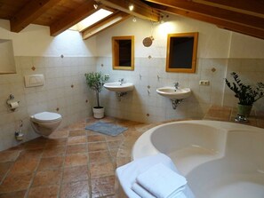 A bathroom with a bathtub, two sinks, a toilet, and a potted plant. - Berg-loft Ramsau (Ramsau bei Berchtesgaden)