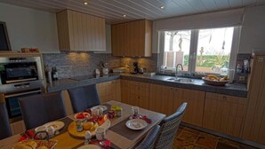 Une cuisine moderne avec des meubles en bois, un four encastré et un coin repas aménagé pour prendre un repas.