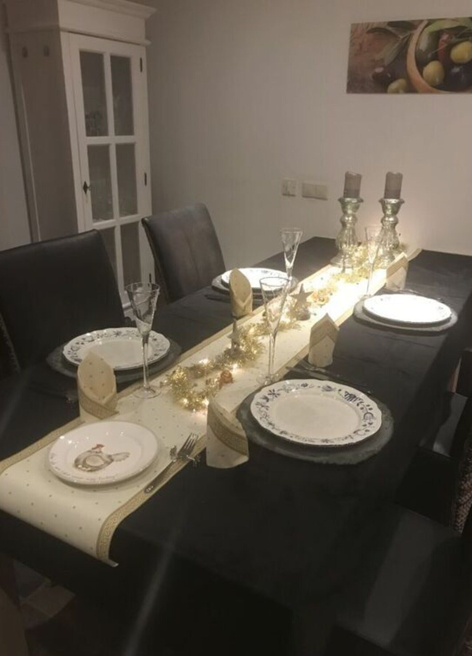 A dining table set with plates, glasses, and candles, featuring a decorative garland.