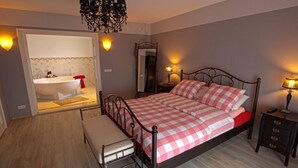 Une chambre à coucher avec un lit, une table de chevet, une commode et une salle de bain visible à travers une porte ouverte.