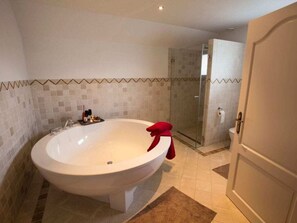Ein Badezimmer mit einer großen Badewanne, einer Duschkabine und einem WC.