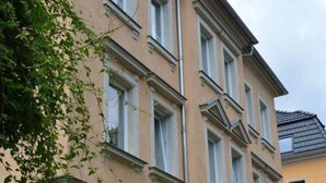 Un edificio de varios pisos con fachada color crema, ventanas amplias y un balcón visible.