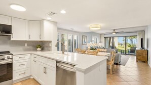 A modern kitchen with white cabinets, a central island, and a dining area with a table and chairs.