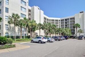 Un hôtel à plusieurs étages doté d’un parking, de palmiers et surplombant un ciel dégagé.