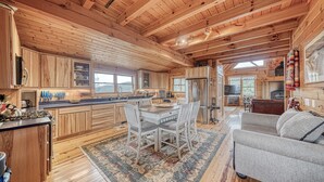 A spacious wooden cabin interior with a dining area, kitchen, and living room.