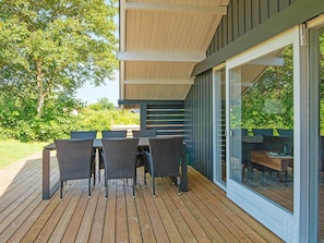 A deck with a table and chairs, a pergola overhead, and a glass door leading to a garden. - 4 Person Holiday Home in Egernsund (Broager)