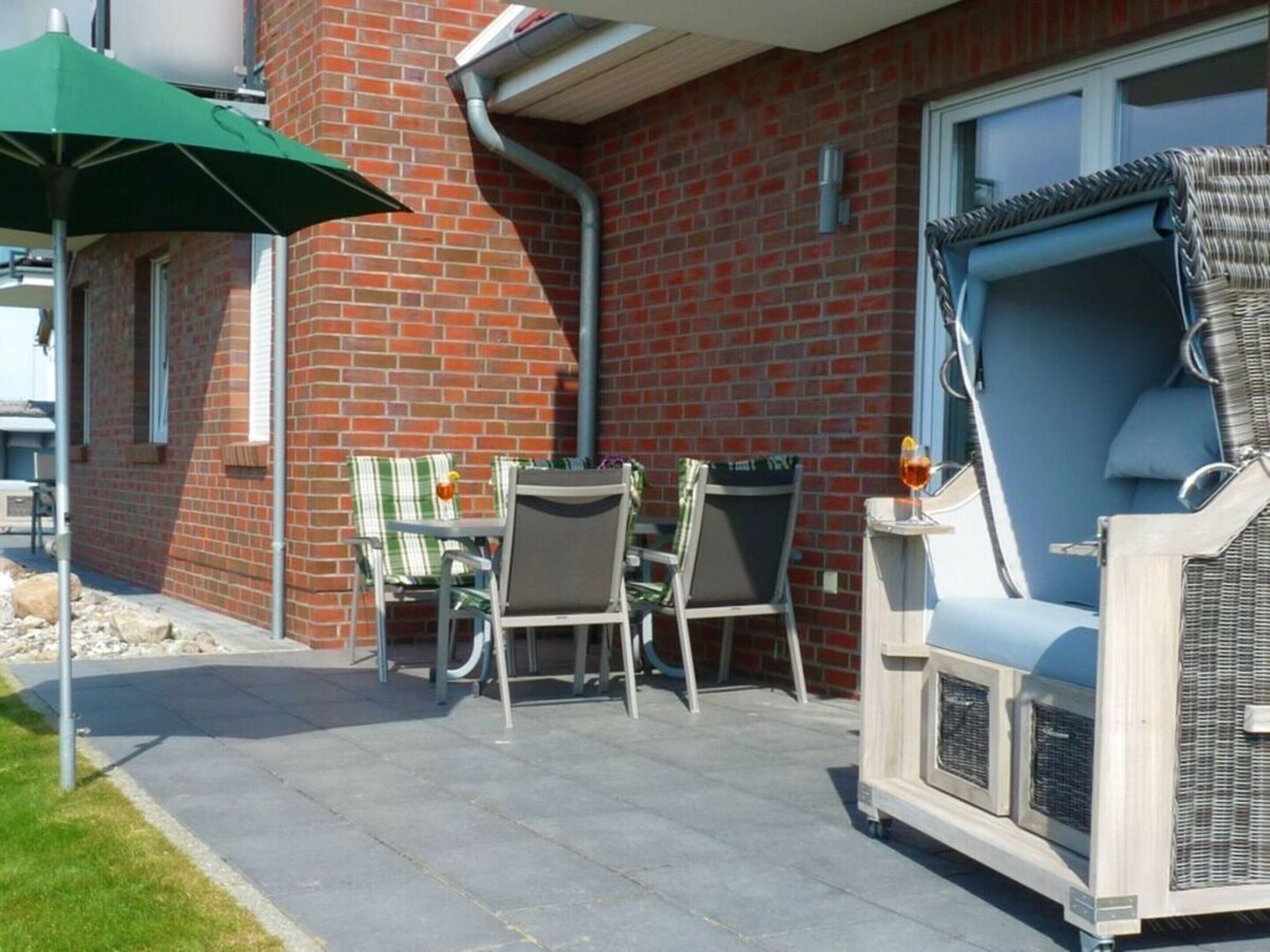 A patio with outdoor furniture, a grill, and a brick wall.