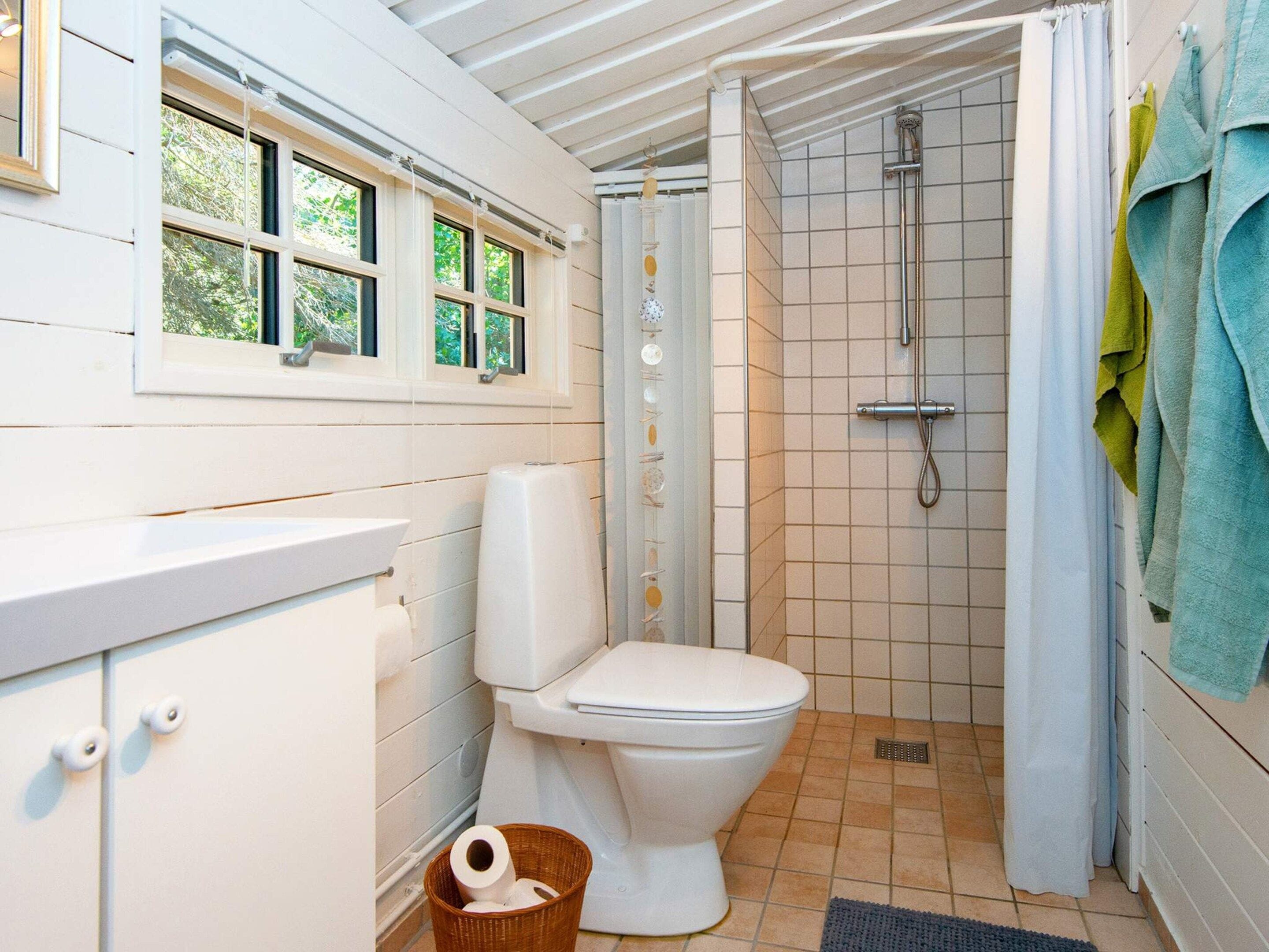 Een badkamer met toilet, douche en raam.