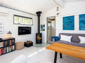 A cozy living room with a fireplace, a sofa, a coffee table, a bookshelf, and artwork on the wall. - 5 Person Holiday Home in Ulfborg (Ulfborg)