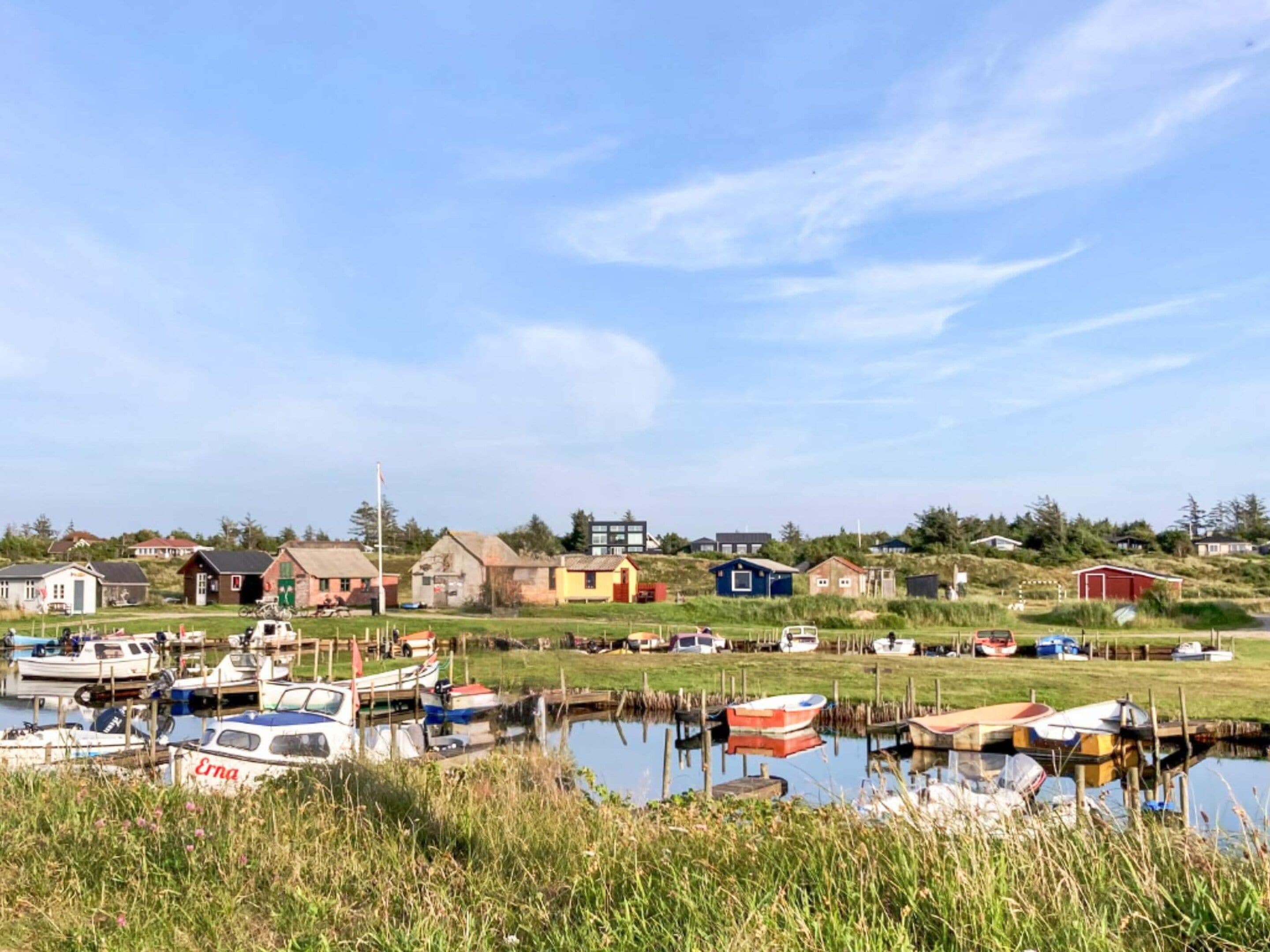A marina with boats docked, surrounded by houses and greenery.