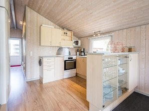 A modern kitchen with wooden cabinetry, a microwave, and a glass-fronted cabinet with dishes.