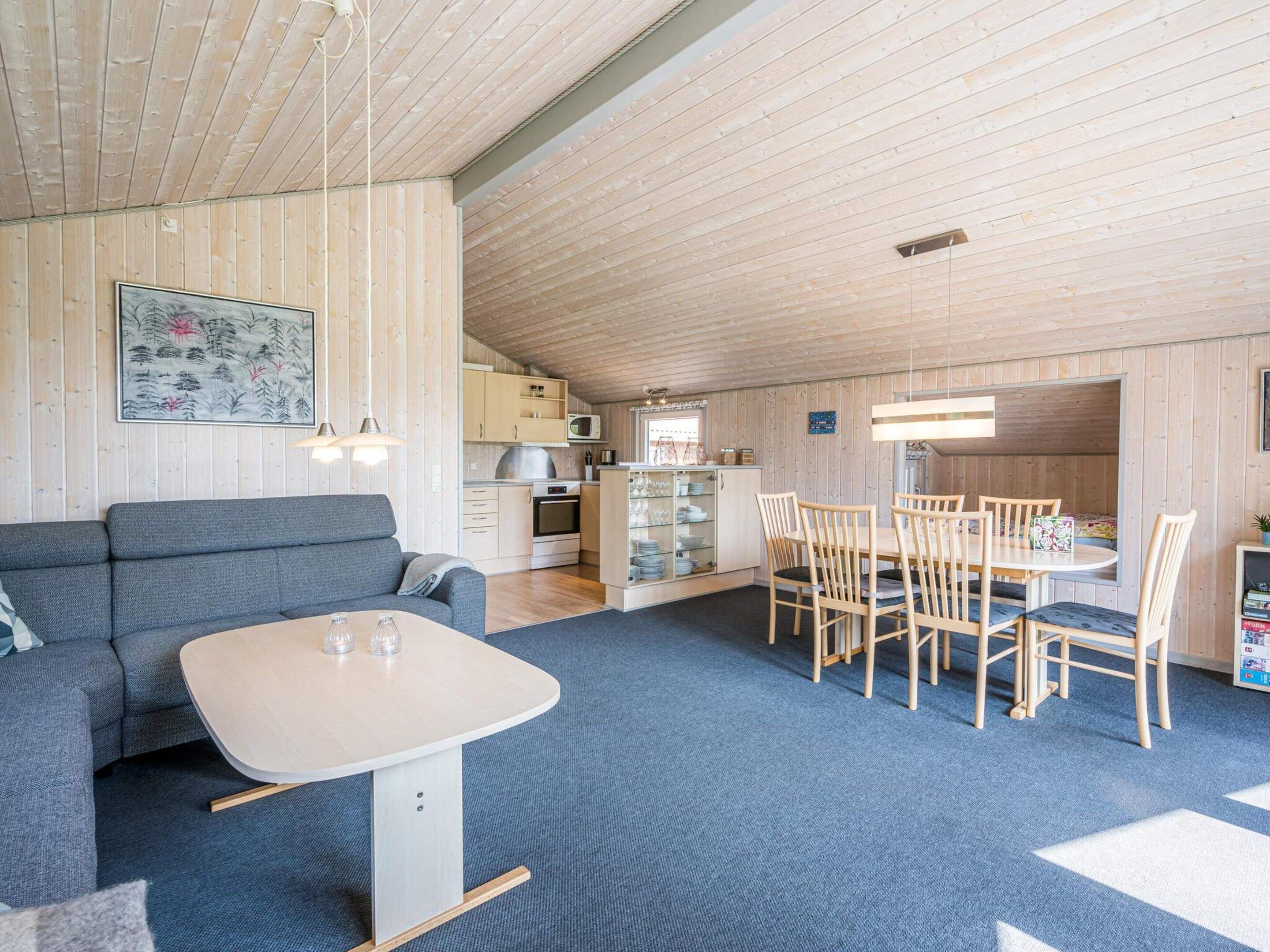 A cozy interior with a sofa, dining table, chairs, and a kitchen area.