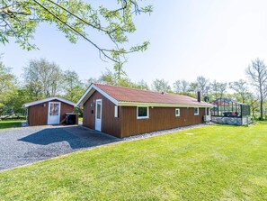 A two-story building with a red roof, a small attached garage, and a covered outdoor area with a basketball hoop. - 4 Person Holiday Home in Hemmet (Hemmet)