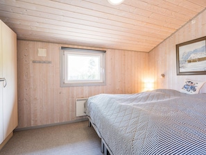 A bedroom with a bed, a window, and a wall-mounted lamp.