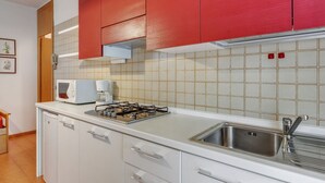 A compact kitchen with white cabinets, a red backsplash, a microwave, a coffee maker, and a stainless steel sink. - Comfortable Apartment in Garda With Swimming Pool (Garda)
