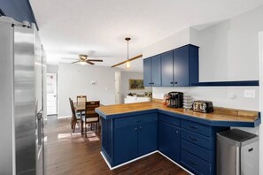A modern kitchen with blue cabinets, a wooden countertop, and stainless steel appliances. - Sleeps 16 · 13 Min to Downtown · Hot Tub & Arcade (Asheville)