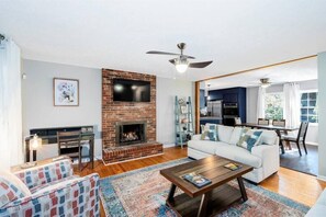 A living room with a fireplace, a sofa, a coffee table, and a television. - Sleeps 16 · 13 Min to Downtown · Hot Tub & Arcade (Asheville)