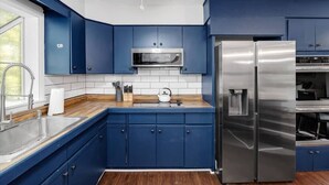 Una cocina moderna con armarios azules, electrodomésticos de acero inoxidable y encimera de madera.