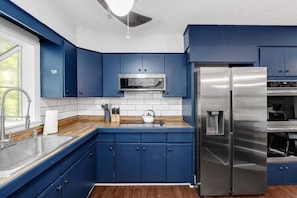 Una cocina moderna con armarios azules, electrodomésticos de acero inoxidable y encimera de madera.