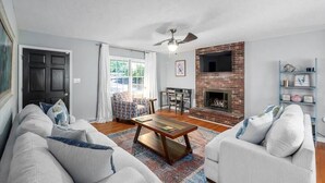 Una sala de estar con chimenea, ventilador de techo y un conjunto de sofás.