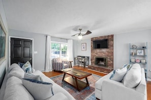 Una sala de estar con chimenea, ventilador de techo y un conjunto de sofás.