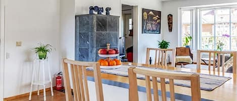 Un comedor con una mesa y sillas de madera, una exhibición de frutas y vistas al exterior a través de amplios ventanales.