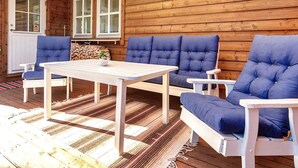 A wooden cabin with a dining table, blue cushioned chairs, and a large window. - 4 Person Holiday Home in Motala (Motala)
