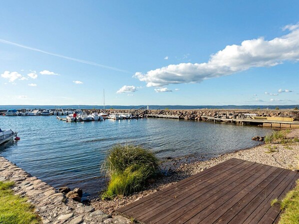 A marina with boats docked, a wooden walkway, and a clear sky. - 4 Person Holiday Home in Motala (Motala)
