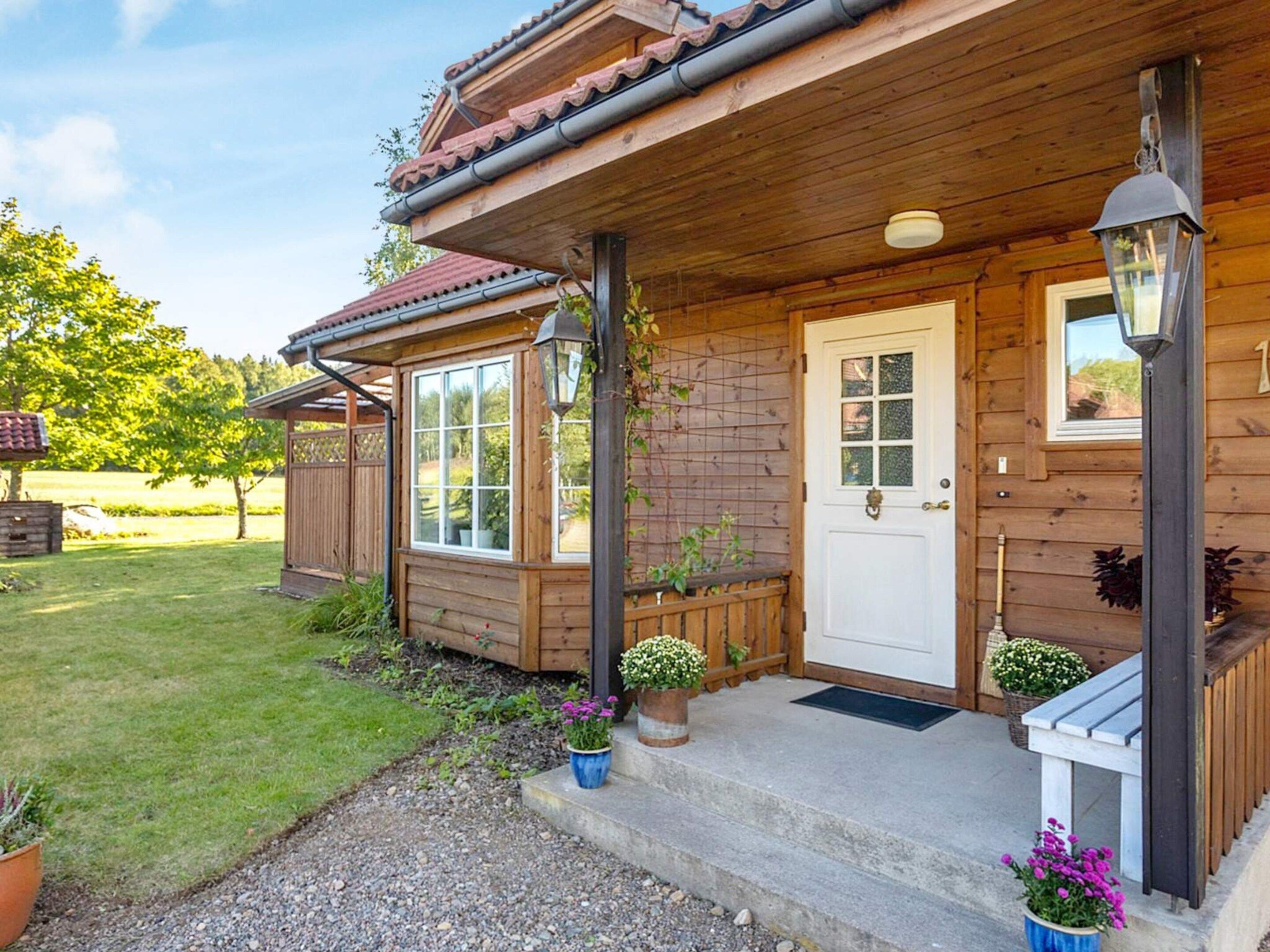 A wooden cabin with a porch, a front door, and a small window.