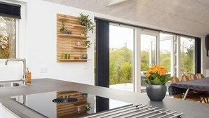 A modern kitchen with a large island, built-in shelves, and a view of the outdoors. - 4 Star Holiday Home in Allingabro (Allingåbro)