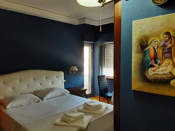 Un dormitorio con una cama grande, una mesita de noche, una silla y un cuadro en la pared.