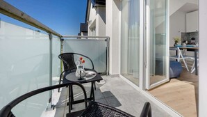 Un balcone moderno con una porta vetrata che dà su una cucina, arredato con un tavolo e sedie.