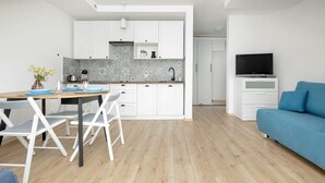 Una cucina moderna con mobili bianchi, una parete di sfondo grigia e un'area pranzo con tavolo e sedie.