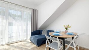Un soggiorno moderno con un divano blu, un tavolo rotondo in legno con piatti blu e sedie bianche.