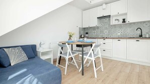 Una cucina moderna con mobili bianchi, un piano di lavoro in legno e un'area pranzo con sedie bianche.