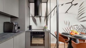 Eine moderne Küche mit Einbauofen, Kaffeemaschine und einem Essbereich mit rundem Tisch und Stühlen.