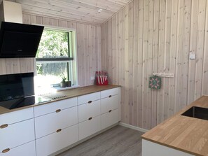 Una cucina con un piano di lavoro in legno, mobili bianchi e una finestra.