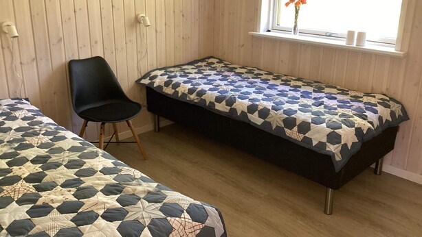 A room with two beds, a chair, and a window with a view. - 8 Person Holiday Home in Hals (Hals)