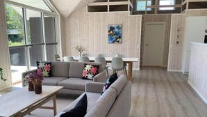A modern interior with a sofa, dining table, and chairs. There is a painting on the wall and a door leading to another room. - 8 Person Holiday Home in Hals (Hals)