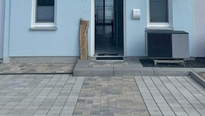 Una casa de dos pisos en azul claro, con una puerta principal negra, dos ventanas en el piso superior y una antena parabólica a la derecha.