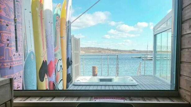 Una habitación con vista al mar, un jacuzzi y tablas de surf apoyadas en la pared.