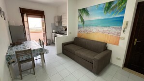 Um espaço compacto com cozinha compacta, área de refeições e um grande mural com tema de praia na parede.