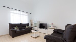 A modern living room with two dark sofas, a white coffee table, a flat-screen TV, and a white cabinet. - Belvilla by OYO Casa A-a3 Corralejo (La Oliva)