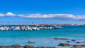 A marina with boats docked, calm water, and a clear sky. - Belvilla by OYO Casa A-a3 Corralejo (La Oliva)