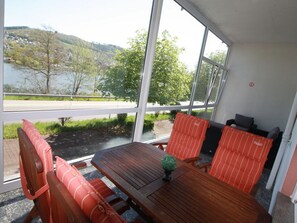 Una mesa de madera con cojines a rayas, una pequeña planta en maceta y vistas a un lago y colinas.